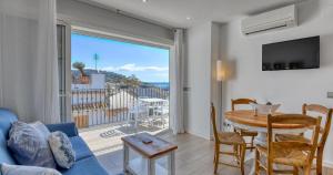 a living room with a blue couch and a table and a large window at Sant Roc Apartments a Minute From The Beach in Calella de Palafrugell