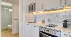 a white kitchen with a sink and a toilet at Sant Roc Apartments a Minute From The Beach in Calella de Palafrugell +90 photos