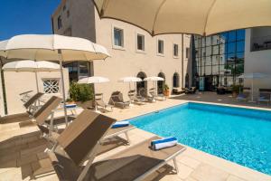 a pool with chairs and umbrellas next to a building at Hotel Lipa in Postira