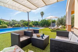 a patio with chairs and an umbrella and a pool at Casa Rural Villa Manantial in La Puebla de Cazalla