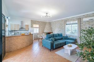 a living room with a blue couch and a kitchen at Casa Rural Villa Manantial in La Puebla de Cazalla