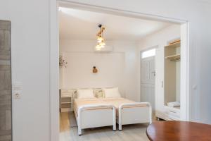 a white room with a bed and a table at Zorbas Studios in Lefkos Karpathou