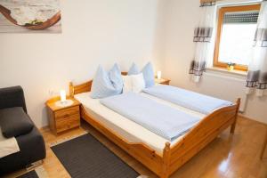 a bedroom with a bed with blue pillows and a chair at Obst- und Weinbauernhof BERNHARD in Leutschach
