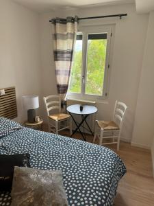 a bedroom with a bed and chairs and a window at la Pause Pyrénées in Maubourguet