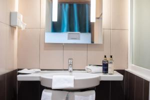 a bathroom with a white sink and a mirror at Elema Hotels Beauvais ex Hostellerie Saint Vincent Beauvais Aeroport in Beauvais