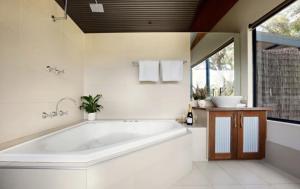 a white bathroom with a large tub and a window at SilverSprings Spa Retreat Pet Friendly Cottages and Glampings in Metricup +116 photos