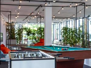 a pool table in a room with plants at ibis Styles Darmstadt in Darmstadt