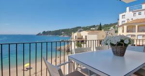 a table with a vase of flowers on a balcony at Exclusive Position Front Line Apartments Calau in Calella de Palafrugell