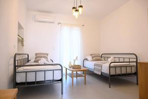 a bedroom with two beds and a table and a window at MarGo House Kythnos in Kithnos