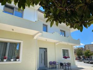 a building with chairs and a table in front of it at Guest House Nuhellari - Family stay & Breakfast near Osumi Canyons in Çorovodë