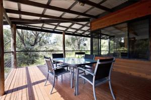 a dining table and chairs on a deck with a view at SilverSprings Spa Retreat Pet Friendly Cottages and Glampings in Metricup