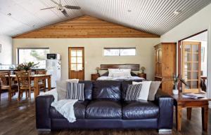 a living room with a black leather couch and a table at SilverSprings Spa Retreat Pet Friendly Cottages and Glampings in Metricup