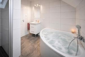 a white bathroom with a tub and a sink at Der VechteSchober - Nordhorn in Nordhorn