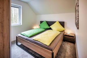 a bedroom with a bed with green and yellow pillows at Der VechteSchober - Nordhorn in Nordhorn