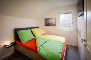 a bedroom with a bed with green and orange pillows at Der VechteSchober - Nordhorn in Nordhorn +32 photos