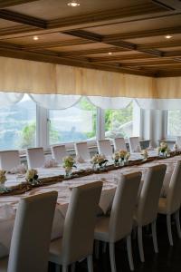 a long table in a room with white chairs and windows at Naturhotel Wieserhof in Longostagno