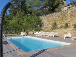 a swimming pool with white chairs and a wall at Domaine de Christin Studios-Hôtel in Junas