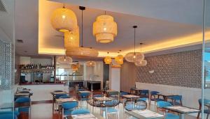 a restaurant with blue chairs and tables and chandeliers at Hotel Vértice Chipiona Mar in Chipiona