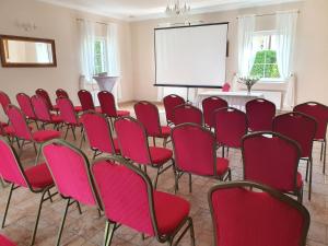 a conference room with red chairs and a white screen at Dwór Zielone Wzgórza in Bukowno