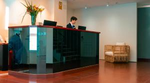 a man standing at a desk with two laptops at Hotel Vértice Chipiona Mar in Chipiona