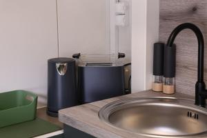 eine Küchenarbeitsplatte mit Spüle und Mischbatterie in der Unterkunft Glamping L tiny , 2Ferienhäuser mit stillvolles Design und hohem Komfort Sauna Hot Tub in Platten + 55 Fotos