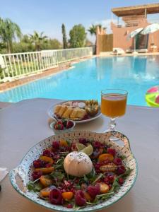 a plate of food and a drink on a table by a pool at Domaine JJ Marrakech in Marrakesh