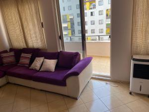a purple couch in a living room with a window at Eretz in Tirana