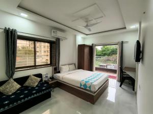 a bedroom with a bed and a couch and a window at Stay Origin, In Nashik in Nashik