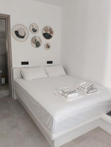 a white bed with plates on the wall at Four season in Ios Chora
