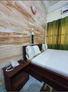 a bedroom with a bed with a phone and a desk at Hôtel Agbégbé in Abomey
