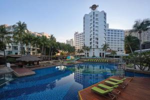 a large swimming pool with chairs and a building at Hard Rock Hotel Pattaya in Pattaya