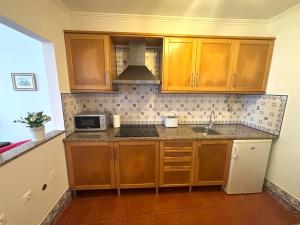 a kitchen with wooden cabinets and a sink and a microwave at CASA DA VILA 2, Sintra in Sintra