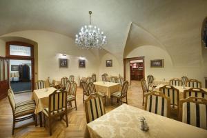 a restaurant with tables and chairs and a chandelier at EA Hotel Hrubá Skála in Hrubá Skála