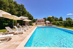 a swimming pool with lounge chairs and umbrellas next to at Apartment Modrusani 1561 in Žminj
