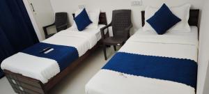 two beds in a room with blue and white pillows at Twin Tag Residency in Chennai