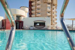 a swimming pool in front of a building at Hotel El Puerto by Pierre Vacances in Fuengirola +49 photos