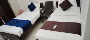two twin beds in a room with a chair at Twin Tag Residency in Chennai