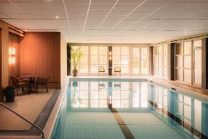 a swimming pool in a building with a table and chairs at Scandic Lillehammer Hotel in Lillehammer