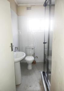 a white bathroom with a toilet and a sink at Sofies's Apartments in Lusaka +30 photos