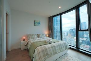 a bedroom with a bed and a large window at Premium 3BR CBD Apt Prime Location in Melbourne