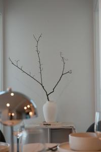 a white vase with a branch in it on a table at Premium 3BR CBD Apt Prime Location in Melbourne