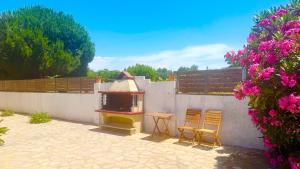 a patio with two chairs and a table next to a wall at TETRAKTYS ESTATE beachside seaview ΥΔΩΡ with big garden in Halikounas