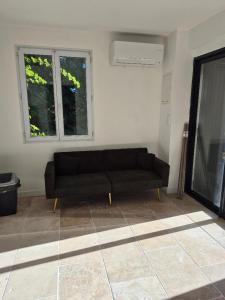 a black couch in a living room with a window at Partie de ferme appartement in Paluds de Noves