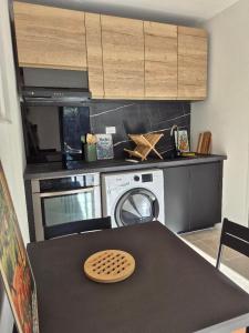 a kitchen with a washing machine and a table at Partie de ferme appartement in Paluds de Noves