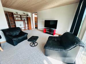a living room with two leather couches and a flat screen tv at Cozy Home - Holiday, Sleepover in Rødbyhavn