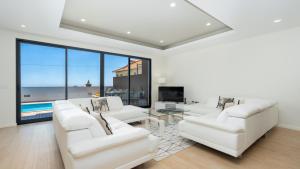 a living room with white furniture and a large window at Evoque Villa by LovelyStay in Arco da Calheta