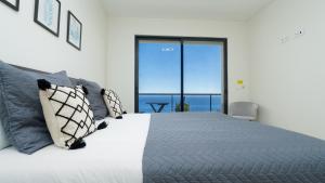 a bedroom with a large bed with a view of the ocean at Evoque Villa by LovelyStay in Arco da Calheta +51 photos