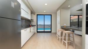 a kitchen with white cabinets and a view of the ocean at Evoque Villa by LovelyStay in Arco da Calheta