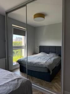 a bedroom with a mirror and a bed and a window at Apartament Krisa z ogródkiem in Pogórze