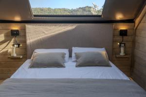 a bed with two pillows in a room with a window at Glamping Pagliaini in Riparbella